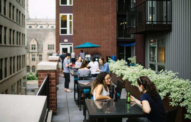 people sitting at tables on a patio in front of a brick building