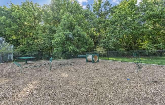 a fenced in dog park with trees in the background