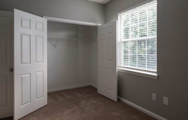 a bedroom with two windows and two closets