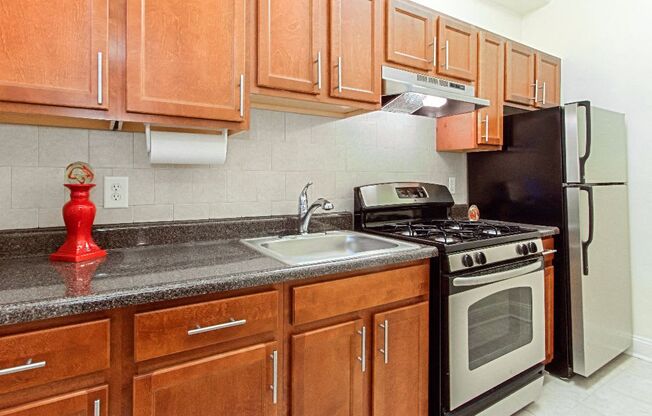 a kitchen with wooden cabinets and stainless steel appliances at the calverton apartment building in washington dc