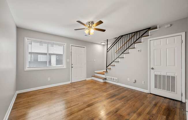 an empty living room with wood floors and a ceiling fan