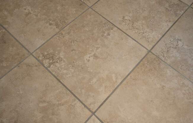 A tile floor with a beige and brown pattern.