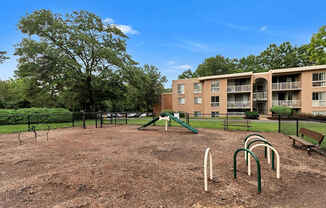 A playground with a green slide and a brown dirt ground.