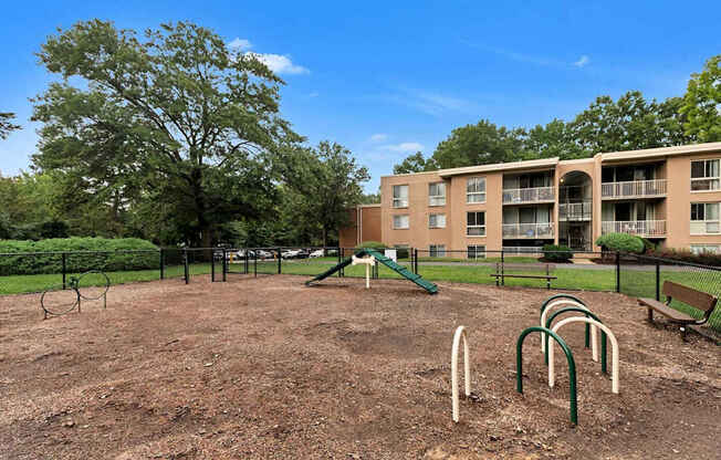 A playground with a green slide and a brown dirt ground.
