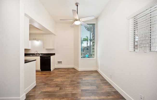 a spacious living room with a kitchen and a ceiling fan