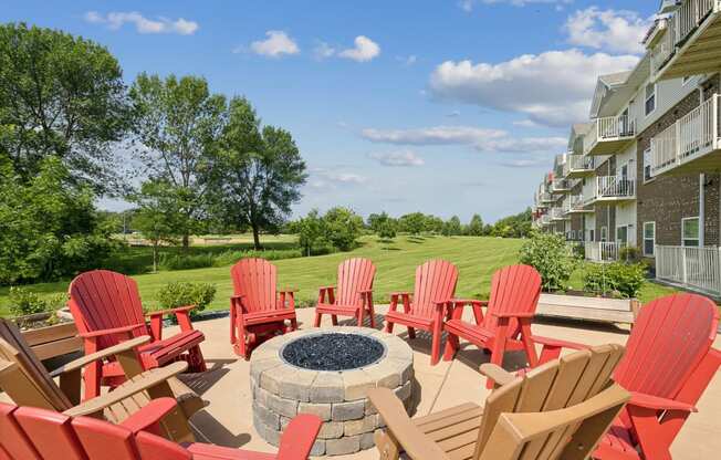 a patio with red chairs and a fire pit and an apartment building