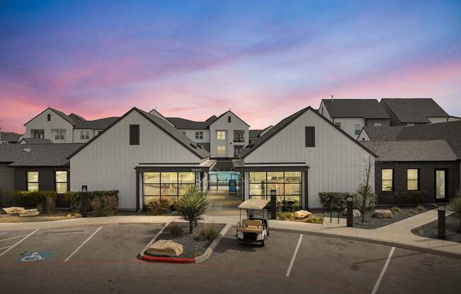 A parking lot in front of a building with a golf cart parked in the lot.