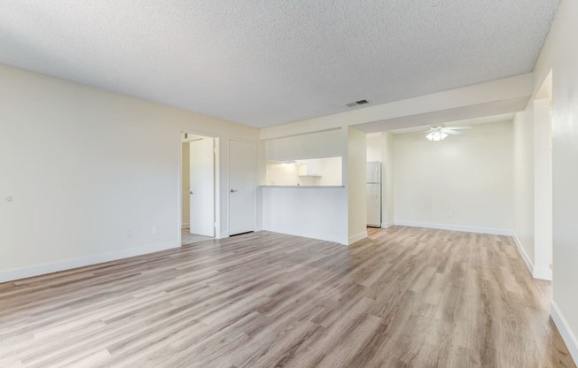 an empty living room with a kitchen in the background  at Redlands Park Apts, Redlands, California