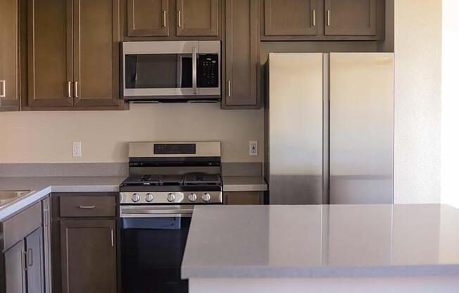 a kitchen with a stove microwave and refrigerator at Loma Villas Apartments in San Bernardino, CA