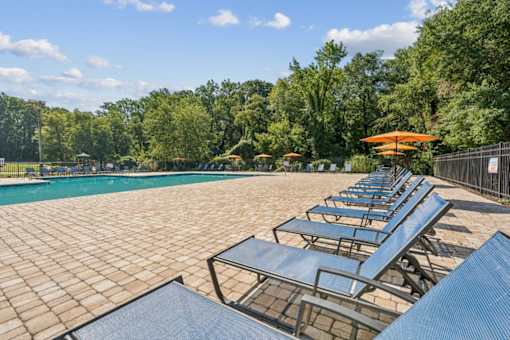 A pool surrounded by trees and sun loungers at Staples Mill Townhomes Apartments, Richmond, VA, 23228