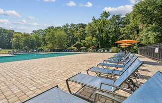 A pool surrounded by trees and sun loungers at Staples Mill Townhomes Apartments, Richmond, VA, 23228