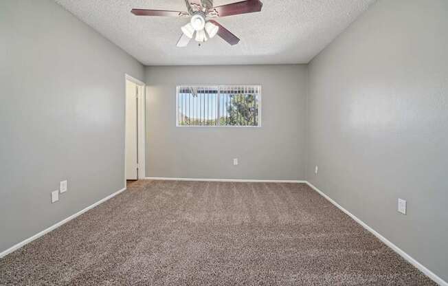 A room with a ceiling fan and carpeted floor.