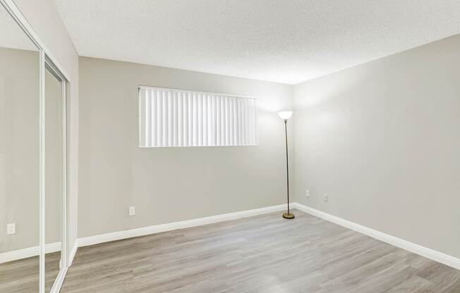 A room with a wooden floor and a floor lamp.