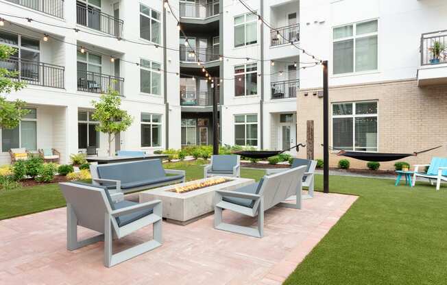 an outdoor patio with chairs and a fire pit in front of an apartment building