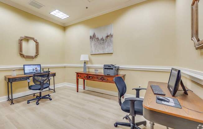 A room with two desks and chairs, one with a laptop and the other with a desktop computer.
