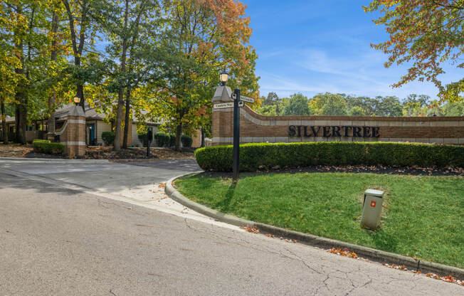 a brick building with a street sign in front of a green lawn and trees