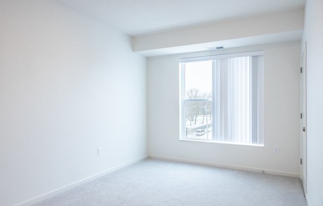 an empty room with a window and white walls