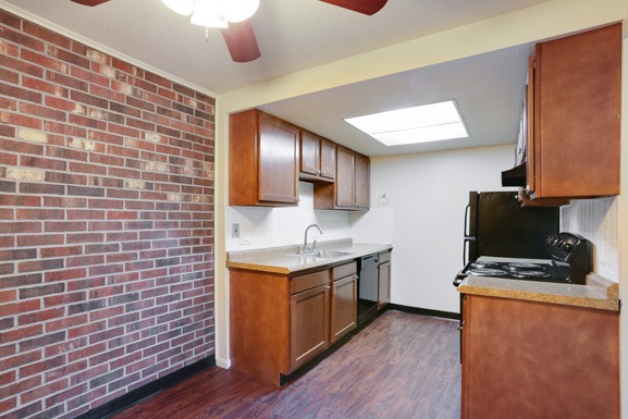 a kitchen with a brick wall and wooden cabinets