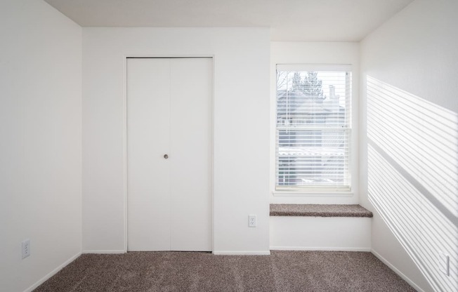 a small window in a room with a carpeted floor and a white door with a window