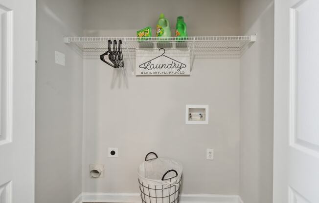 a laundry room with a basket and a sign on the wall and a rack above