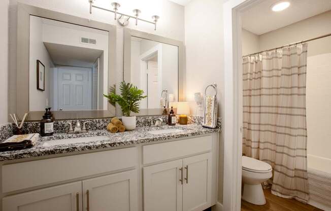 A bathroom with a marble countertop and white cabinets.