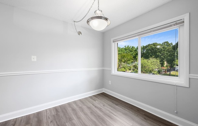 an empty bedroom with a large window and wood flooring