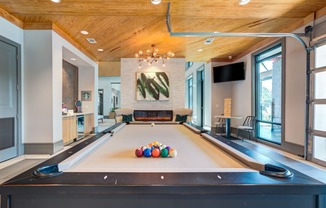 a pool table with balls on it in a large room with a fireplace