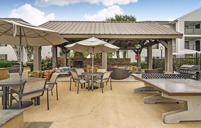 a patio with tables and umbrellas and a fire pit at Avalon Apartment Homes, Mississippi