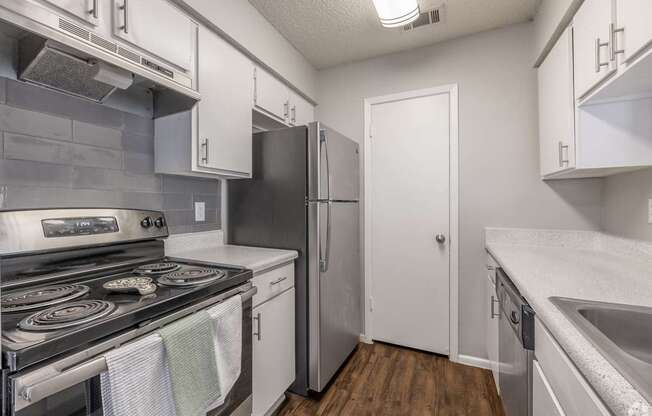 A kitchen with a stove, refrigerator, and sink.