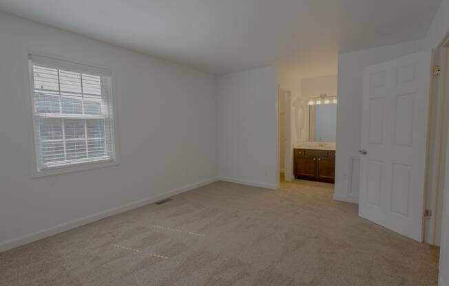 a bedroom with a large window and a door to a bathroom