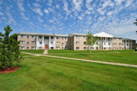 a grassy area with several apartment buildings in the background