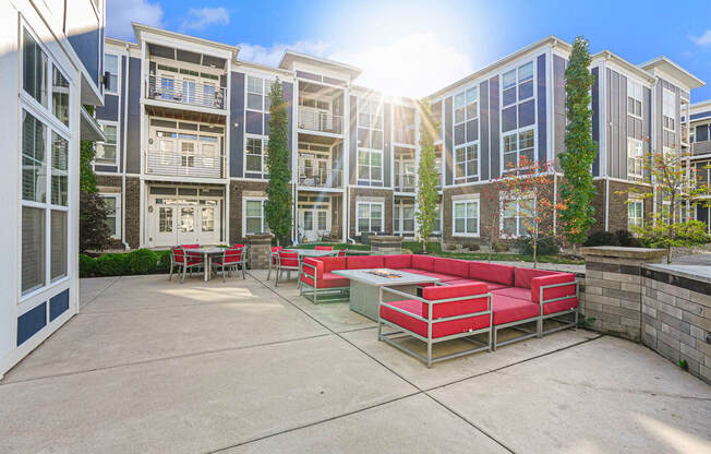 a patio with red couches and a table in front of an apartment building