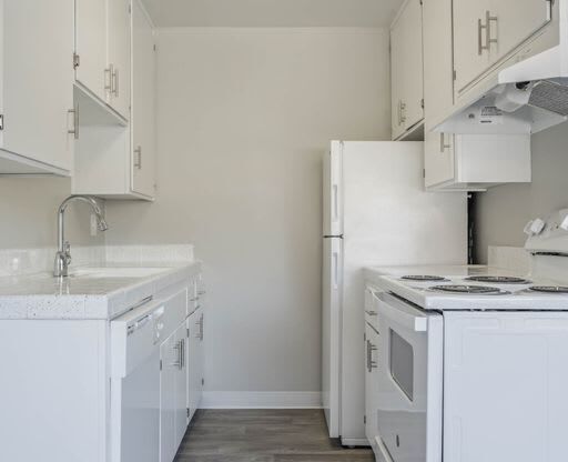 a white kitchen with a stove and a refrigerator at The Arches Apartments, El Cajon, 92021