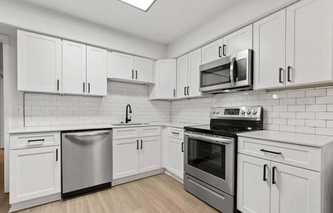 a white kitchen with stainless steel appliances and white cabinets