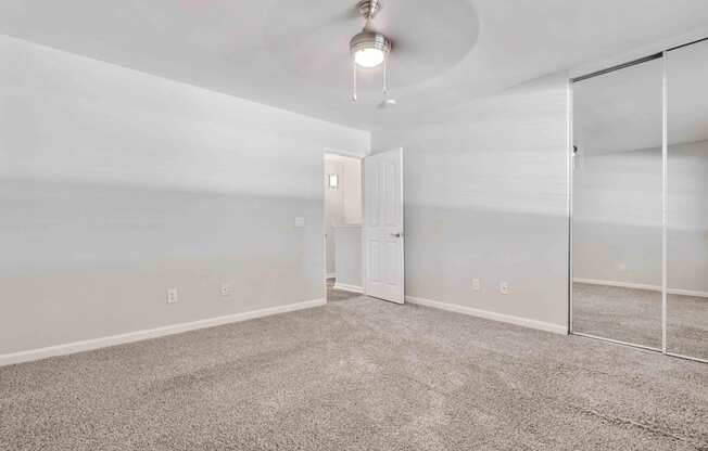 Apartments in San Jose, CA for Rent - Los Gatos Creek - Bedroom with Wall-to-Wall Carpet Flooring, a Ceiling Fan with Light, and a Closet with Sliding Mirror Doors