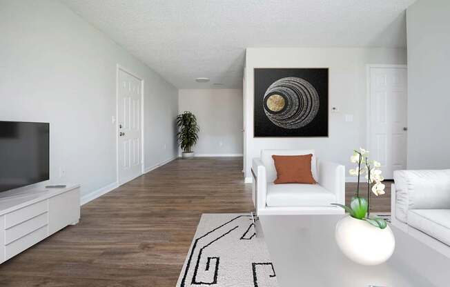 A living room with a white couch, a television, and a painting on the wall.