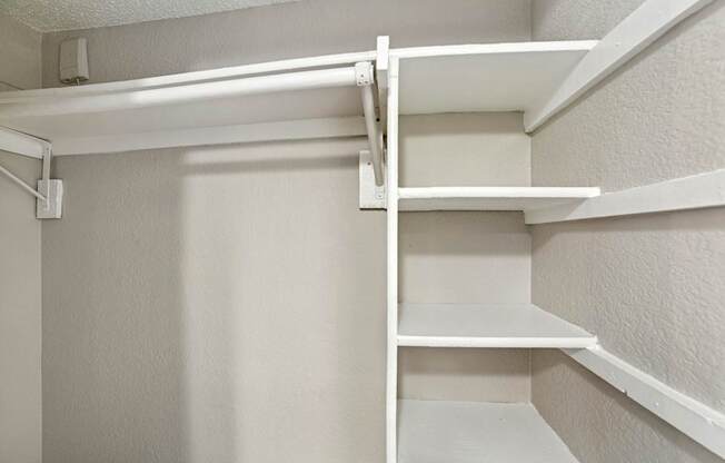 A white shelving unit with four shelves is mounted on a white wall.