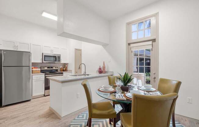 A kitchen with a table set for two with a window in the background.