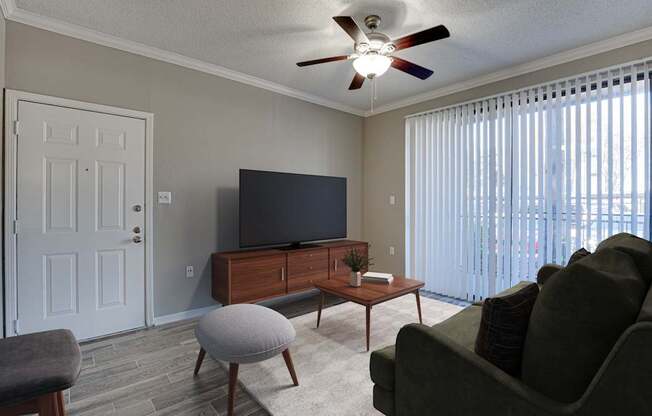 A living room with a grey couch, a wooden coffee table, and a flat screen TV.