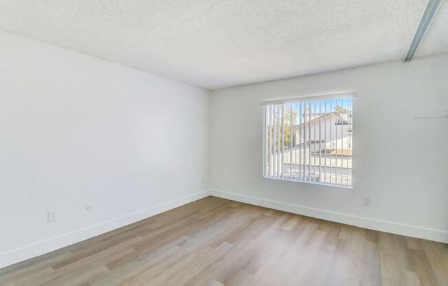 A room with a window and wooden flooring.