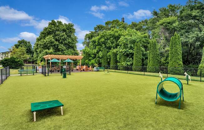 a large grassy area with a swing set and a trampoline