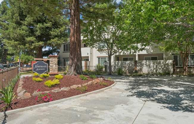 a sidewalk in front of a building with trees and a sign