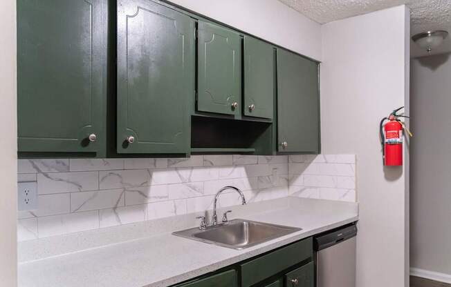 A kitchen with green cabinets and a white counter top.