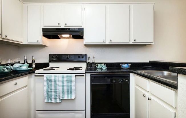 a kitchen with white cabinets and black countertops