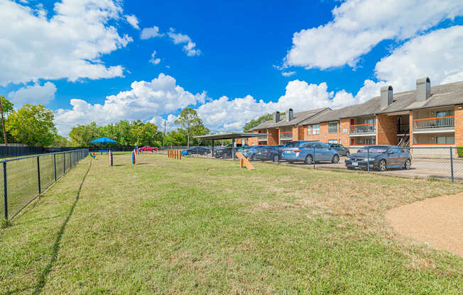 A sunny day at the apartment complex with cars parked in the parking lot.