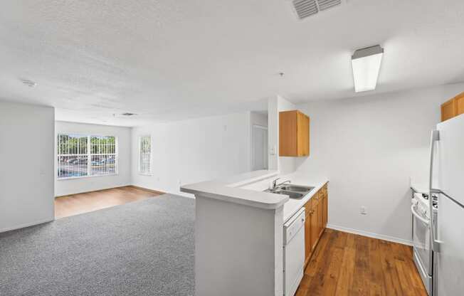 an empty kitchen and living room with white walls and wood floors