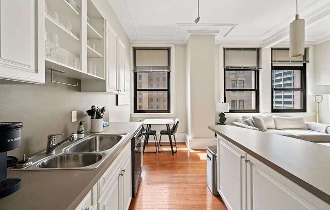 A kitchen with white cabinets and a wooden floor.