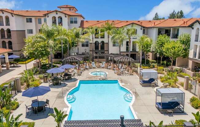 A large swimming pool surrounded by lounge chairs and umbrellas in a resort-like setting.