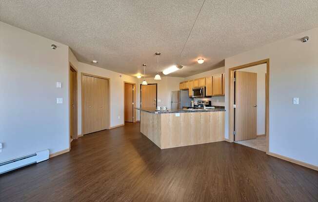 a living room and kitchen with wood floors. Fargo, ND East Bridge Apartments