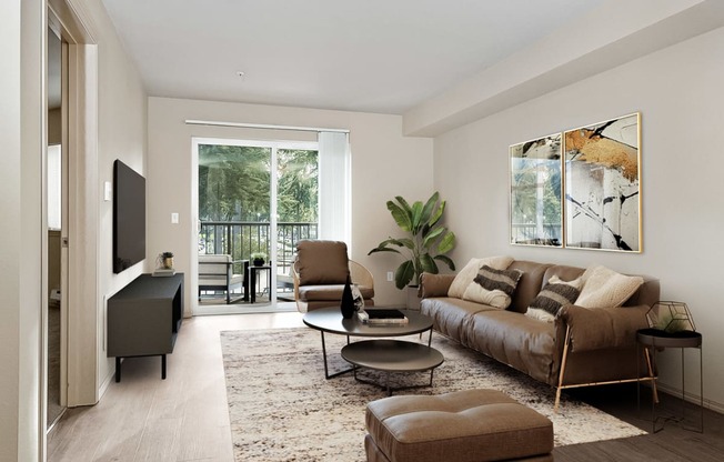 Living room with sliding glass door to the balcony on the far wall, matching chair, couch, and ottoman with a table in the center across from a tv and entertainment unit at 6 Wood Flats, Lacey, WA 985